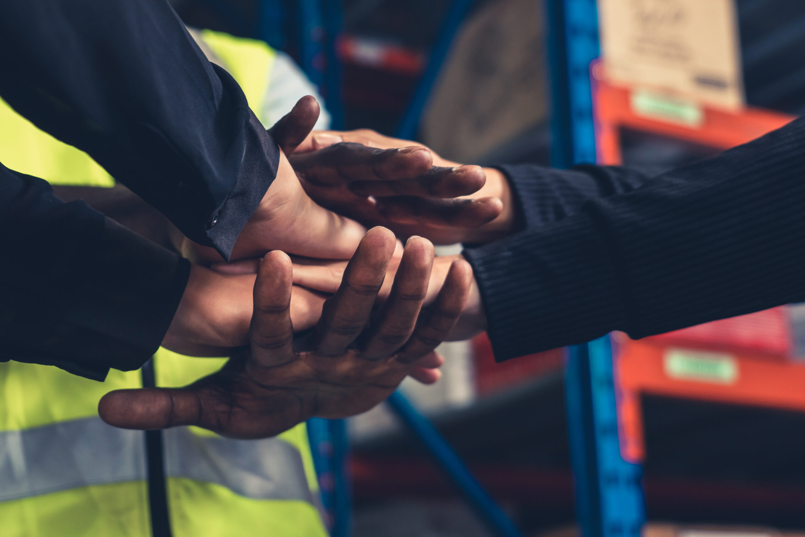 Factory workers stacking hands together in warehouse or storehouse . Logistics , supply chain and warehouse business concept .